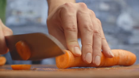 Woman-cutting-carrot-on-table-closeup